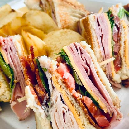 Triangle-cut club sandwiches stacked on a plate.