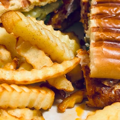 Crinkle-cut fries beside a stuffed pastry roll.