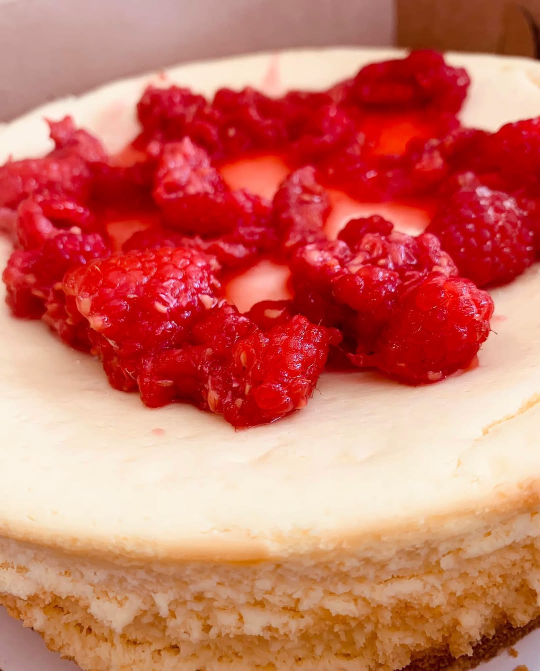 Slice of cheesecake topped with fresh raspberries